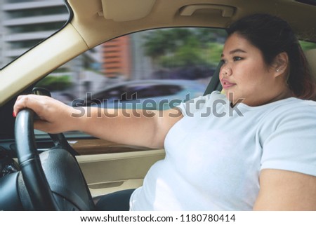 Picture of fat woman driving a car without a seat belt. Shot on the road