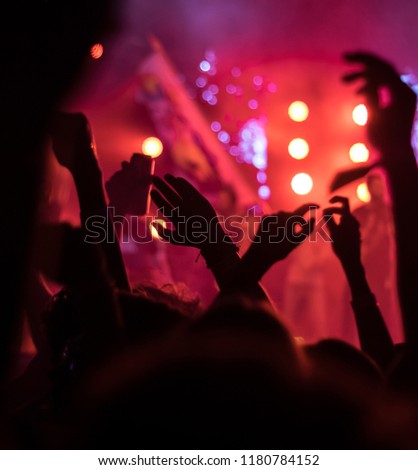 Generic concept image of crowd at open air festival at night. Raised hands and smartphones while applauding.