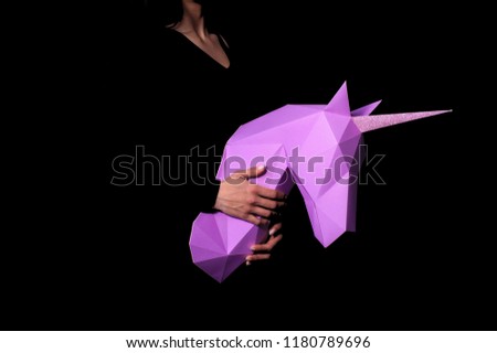 The girl holds a unicorn but a black background