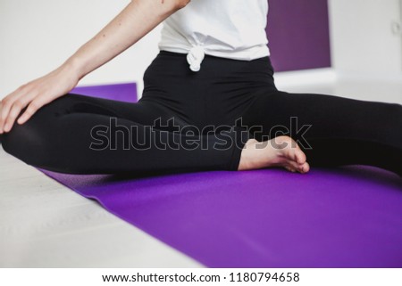Cute graceful girl with long hair in tights engaged in yoga on a lilac rug
