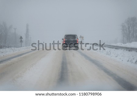 Car with lights on a snow covered road.