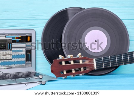 Vinyl records, guitar and laptop. Musical objects on blue wooden background. Modern and vintage musical technology.