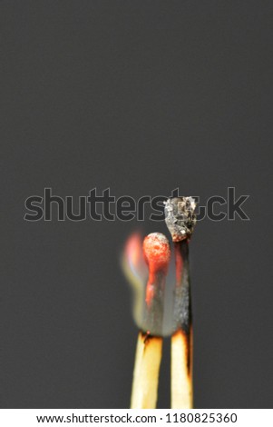 Two burning matches against a black background look like a couple cuddling and being intimate with each other - concept symbolizing fiery love