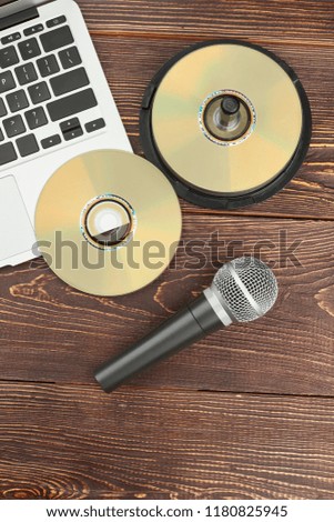 Old and modern devices on wooden table. Portable laptop, compact discs and microphone on wooden background, top view. Technology progress concept.