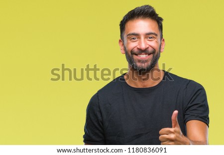Adult hispanic man over isolated background doing happy thumbs up gesture with hand. Approving expression looking at the camera with showing success.