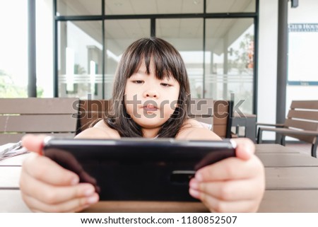 Happy Asian Child girl looking cartoon in smart phone.child, technology and internet concept
