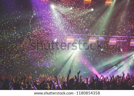A crowded concert hall with scene stage lights, rock show performance, with people silhouette
