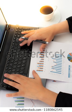 Businesswoman with financial documents using laptop at desk