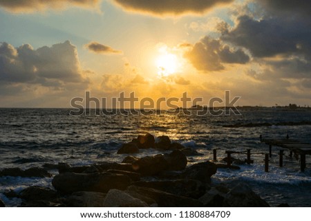 Landscape of the sundown in sea water amongst rocky beach the broken gangway