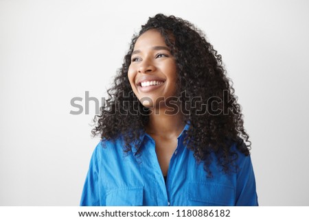 Positive human facial expressions, feeling and emotions. Picture of beautiful happy young dark skinned mixed race female with loose wavy hair looking sideways with dazzling ultra white smile