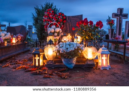 Candles Burning At a Cemetery During All Saints Day.  Royalty-Free Stock Photo #1180889356