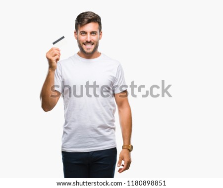 Young handsome man holding credit card over isolated background with a happy face standing and smiling with a confident smile showing teeth