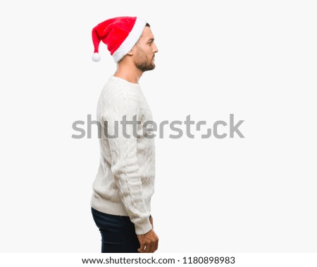 Young handsome man wearing santa claus hat over isolated background looking to side, relax profile pose with natural face with confident smile.