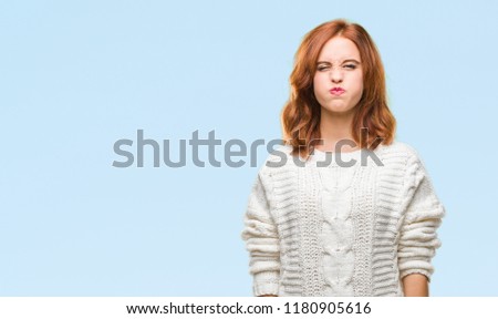 Young beautiful woman over isolated background wearing winter sweater puffing cheeks with funny face. Mouth inflated with air, crazy expression.