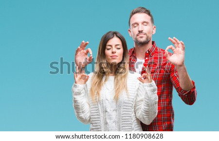 Young couple in love wearing winter sweater over isolated background relax and smiling with eyes closed doing meditation gesture with fingers. Yoga concept.