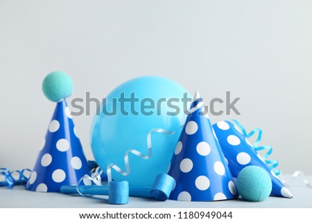 Birthday paper caps with blowers and balloon on grey background
