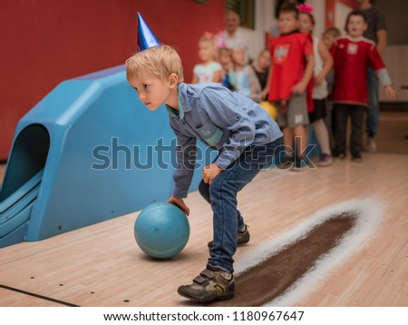 Six years old boy playing bowling during birthday party.