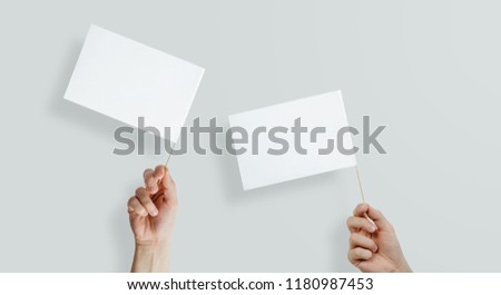 Two white flags held in hands on a light, pastel background. The concept of completing content, manifestations and protesting. Expressing your own views, passing on information.