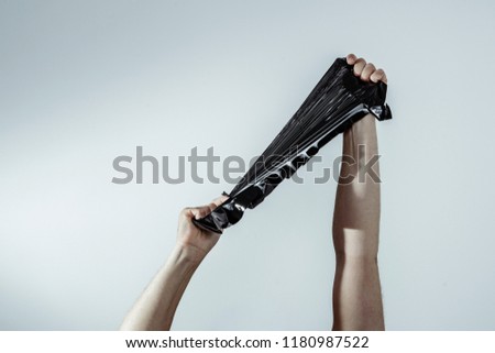 Hands stretch black foil stretch. A view of a hand holding a black foil trying to kidnap her. The concept of destruction, unpacking shipments, packaging problems. Royalty-Free Stock Photo #1180987522