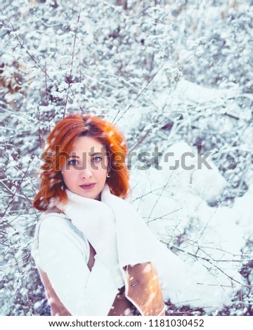 Stylish young girl walking in a winter day on the background of the park with snow.