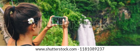 Hawaii travel tourism. Tourist woman taking pictures with mobile phone photo app of Wailua Falls waterfall on Kauai, Hawaii, USA.