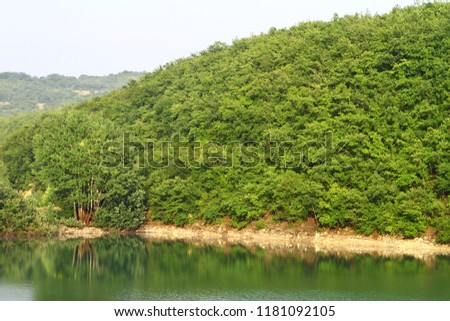Natural landscape photo - pretty still lake with green hills in distance.
