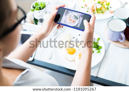 High angle closeup of unrecognizable young woman taking photo of beautiful food via smartphone while enjoying lunch in cafe, copy space