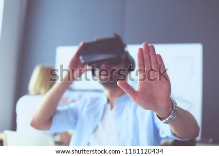 Young male software programmer testing a new app with 3d virtual reality glasses in office.