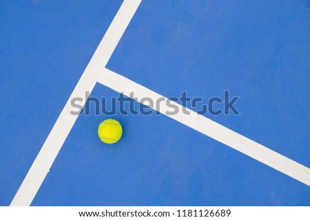 Graphic sports background of yellow tennis ball laying on blue floor in court, copy space Royalty-Free Stock Photo #1181126689