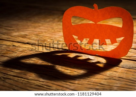 Halloween background decoration holiday concept. Jack O pumpkin funny face shadow and silhouette on wooden table