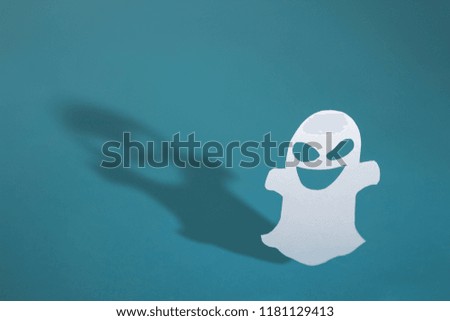 Halloween background decor holiday concept. Funny ghost and graphic shade, hard light on blue table.