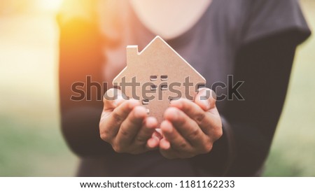 Small home model on woman hand. Family life and business real estate concept. Vintage tone filter effect color style.