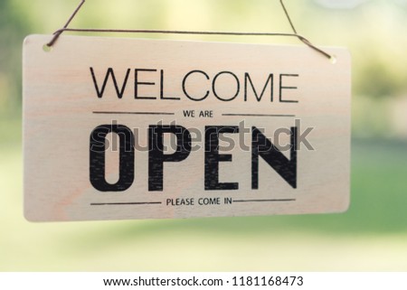 Open sign broad through the glass of door in cafe with colorful bokeh light abstract background. Business service and food concept. Vintage tone filter effect color style.