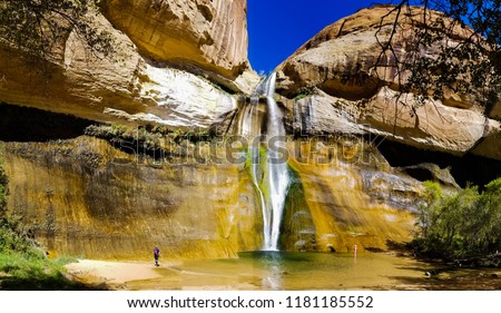 Hikers wading in the waters below Lower Calf Creek Falls in the Grand Staircase Escalante National Monument in Utah Royalty-Free Stock Photo #1181185552