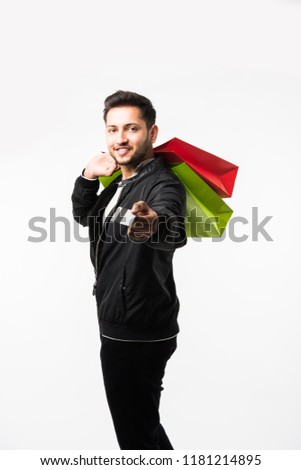 Indian/asian man showing his shopping bags and credit or debit card while standing over white background