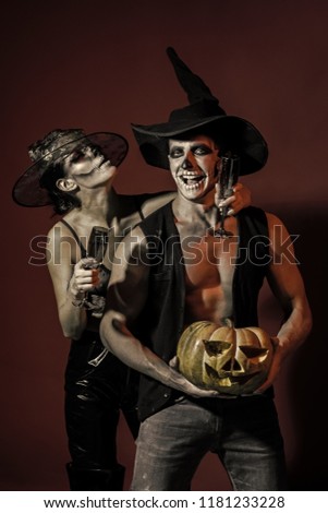 Halloween Zombie party and horror. Couple in love with pumpkin and wine glass. Holiday and celebration. Halloween couple with makeup on brown background. woman and man has happy face in witch hat.
