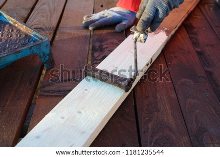 Home improvement - handywoman painting wooden plank outdoors