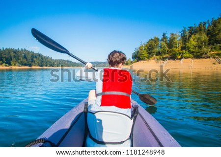 Strong young girl kayaking on the Lokvarsko lake in Gorski kotar, Croatia. Active girl having enjoying adventurous experience on a sunny day.