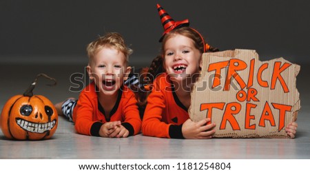 happy Halloween! cheerful children in costume with pumpkins on a grey background
