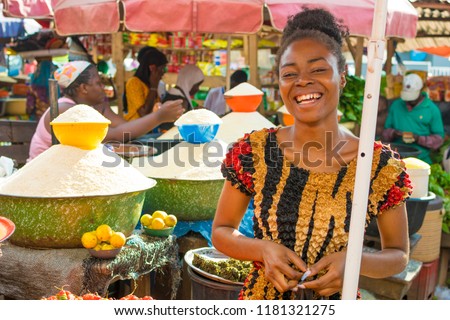 young african girl smiling in a local african market  Royalty-Free Stock Photo #1181321275