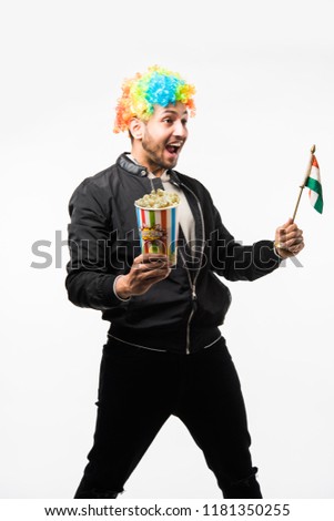 Indian young man holding national tri colour flag while cheering for indian team