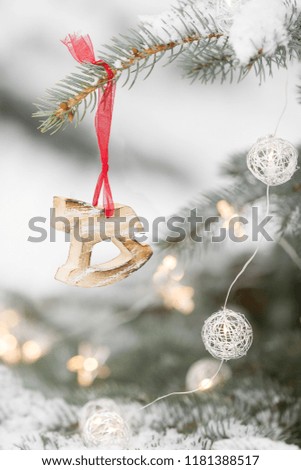 Christmas decoration on a red ribbon on a snowy Evergreen tree outdoors. Winter, Christmas celebration, holidays season.