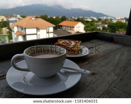 New day, restart yourself by a cup coffee. Take pictures of a cup of 3 in 1 coffee on wood table with mountian view from hotel.