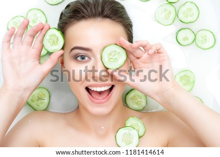 Portrait of beauty caucasian female woman with clean pure skin taking spa relaxing in bath with cucumber slices white soap shampoo water. Skin beauty health care concept. Body part bare shoulder Royalty-Free Stock Photo #1181414614