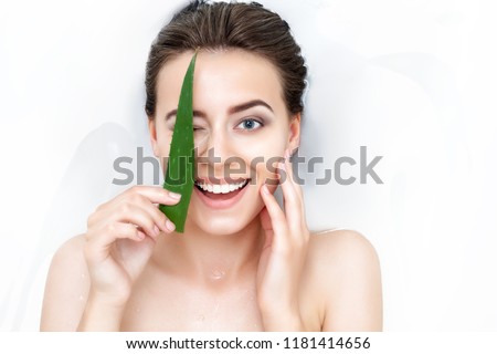 Portrait of young female woman adult with clean pure skin taking spa smiling relaxing in bath with aloe white soap shampoo water. Skin beauty health care concept. Body part bare shoulder Royalty-Free Stock Photo #1181414656