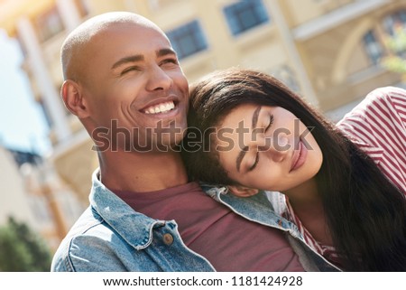 Romantic Relationship. Young diverse couple sitting on the city street hugging girlfriend sleeping on boyfriends shoulder smiling happy close-up