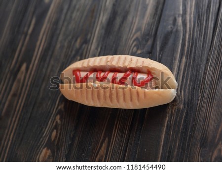 hotdog with tomato sauce on dark wooden background.photo with co