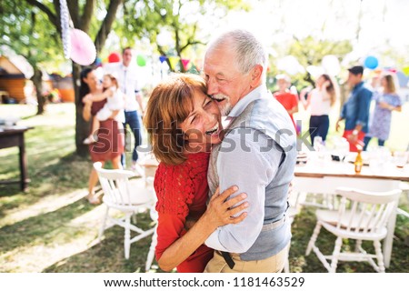 A senior couple dancing on a garden party outside in the backyard.