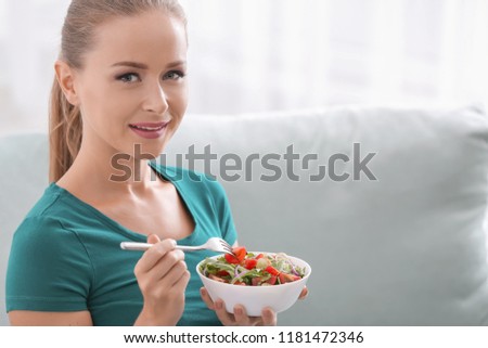 Beautiful woman eating fresh vegetable salad at home