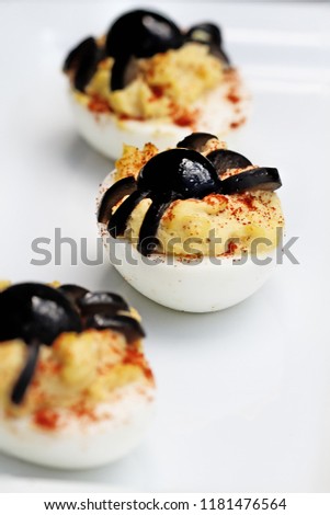 Fun food for kids. Halloween boiled eggs with black olive spiders on top of them. Extreme shallow depth of field with selective focus on center egg. Altnerative to candy.